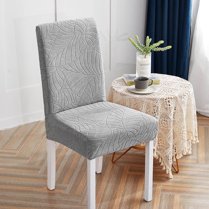 Gray grey textured chair cover on a chair in a room with a small table and decorative items.